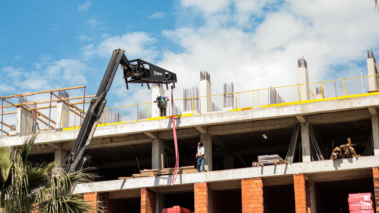 Crane operating on a building construction site with workers visible.